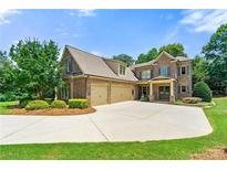 Stunning two-story brick home featuring a three-car garage, well-manicured lawn, and lush landscaping at 2317 Whiting Bay Courts Nw, Kennesaw, GA 30152