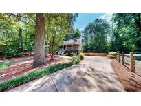 Quaint home with a covered porch, surrounded by lush greenery and a long driveway at 203 Cedar Creek Ct, Acworth, GA 30101