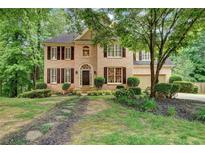Charming two-story brick home with a well-manicured lawn and mature trees at 615 Willowbrook Run, Johns Creek, GA 30022