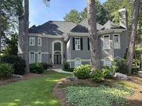 Elegant two-story home with a well-manicured lawn, gray stucco exterior, and black shutters surrounded by mature trees at 1111 Waterford Green Pt, Marietta, GA 30068
