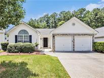 Charming single Gathering home boasts a two car garage, neutral paint, and manicured lawn at 3198 Liberty Commons Dr, Kennesaw, GA 30144