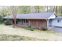 Charming brick home with a covered porch, mature trees, and well-maintained landscaping at 276 Colewood Nw Way, Atlanta, GA 30328
