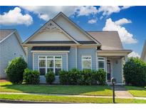 Charming blue home featuring manicured landscaping, a covered front porch, and decorative gable detailing at 903 Duncan Ter, Canton, GA 30115