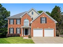 Charming brick two-story home with black shutters, a well-manicured lawn, and a two car garage at 3053 Ramsey Pl, Marietta, GA 30062