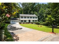 Charming two-story home boasts a manicured lawn and a long driveway leading to an attached garage at 321 Crabtree Court, Marietta, GA 30068