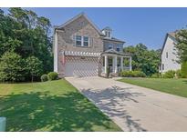 Charming brick home with a well-manicured lawn, inviting front porch and long concrete driveway at 4445 Hager Ct, Cumming, GA 30040