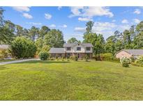 Charming two-story home with a brick and white facade, lush lawn and beautiful landscaping at 425 Houze Way, Roswell, GA 30076