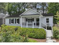 Charming white home featuring a manicured lawn, black shutters, and welcoming front porch at 502 Hascall Nw Rd, Atlanta, GA 30309