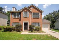 Charming two-story brick home with well-maintained landscaping, complemented by green grass and mature trees at 711 Ashley Ln, Stone Mountain, GA 30087
