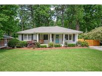 Quaint home featuring a well-manicured lawn and inviting front porch with a cheerful blue door and swing at 963 Turner Se Dr, Smyrna, GA 30080