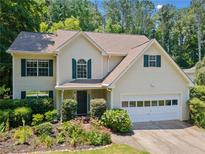 Charming two-story home featuring a manicured front yard with flowering shrubs and an attached two-car garage at 5340 Harris Creek Dr, Cumming, GA 30040