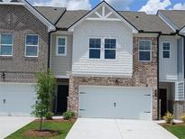 Charming townhome with a two-car garage and a blend of brick and white shingle siding at 553 Tuskegee St # 52, Mcdonough, GA 30252