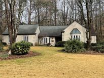 Charming one-story home featuring a well-maintained lawn and mature trees enhancing its curb appeal at 1565 Kings Xing, Smoke Rise, GA 30087