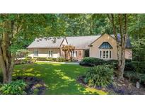 Charming one-story home boasting lush landscaping and mature trees, offering serene curb appeal at 1565 Kings Xing, Smoke Rise, GA 30087