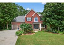 Charming two-story red brick home with black shutters, lush landscaping, and a well-manicured lawn at 505 Armor Knl, Powder Springs, GA 30127