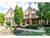Charming brick home with a beautifully landscaped front yard and covered porch at 5347 Harbury Cv, Suwanee, GA 30024