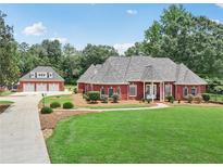 Beautiful brick home features a well-manicured lawn, lush landscaping, and a detached three-car garage at 2631 Young Rd, Stone Mountain, GA 30088