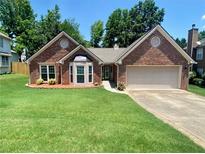 Charming one-story brick home featuring a manicured lawn, bay window, and attached two-car garage at 5022 Anclote Dr, Alpharetta, GA 30022