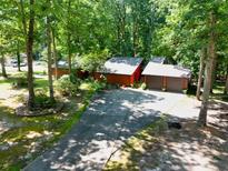 Unique exterior featuring two-car garage and a driveway, surrounded by mature trees and lush greenery at 686 Hillwood Ct, Dacula, GA 30019