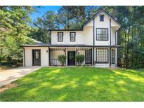 Charming two-story home with black trim, well-manicured lawn, and lush trees at 534 Woodcrest Manor Dr, Stone Mountain, GA 30083