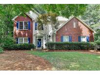 Charming two-story home featuring a brick facade, blue shutters, and a well-manicured front lawn at 6520 Fairfield Trce, Suwanee, GA 30024