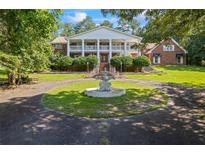 Stately two-story brick home with white columns and a circular driveway featuring a charming water fountain at 1961 Luke Edwards Rd, Dacula, GA 30019