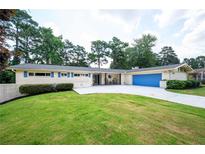 Charming one-story home with a blue garage door and a well-maintained front lawn and a white brick exterior at 2302 Springside Way, Decatur, GA 30032