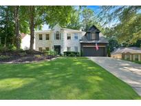 Charming white-brick home featuring a well-manicured lawn and a two-car garage with an American flag at 4385 Pinehollow Court Ct, Alpharetta, GA 30022