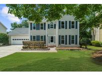 Charming two-story home with a well-maintained lawn, attached garage, and inviting front entrance at 1410 Kingfield Dr, Johns Creek, GA 30005