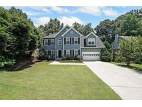 Charming two-story home featuring a well-manicured lawn, two-car garage and mature trees at 5176 Shotwell St, Woodstock, GA 30188