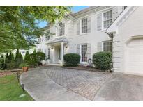 Elegant white brick home with gray shutters, complemented by a meticulously paved driveway and lush landscaping at 7045 Hunters Ne Knl, Sandy Springs, GA 30328