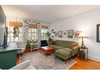 Bright living room featuring hardwood floors, a plush sofa, and sunlit windows adorned with hanging plants at 1166 Virginia Avenue Ne Ave # 8, Atlanta, GA 30306