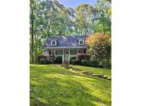 Charming cottage-style home featuring a lush, green lawn and mature trees for added privacy at 713 Trickum Valley Dr, Woodstock, GA 30188