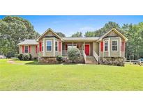 Charming single-story home featuring a well-maintained lawn, stone accents, and inviting red front door at 100 Walnut Ct, Stockbridge, GA 30281