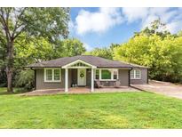 Charming single-story home with well-manicured lawn, mature trees and a cozy front porch with seating at 2123 Garden Cir, Decatur, GA 30032