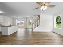 Bright, open-concept living room featuring hardwood floors, a ceiling fan, and a view to the backyard at 5350 Mercedes Dr, Cumming, GA 30041