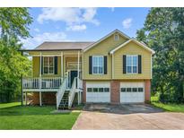 Charming two-story home with a front porch, two-car garage, and landscaped yard at 60 Boardwalk Ave, Covington, GA 30016