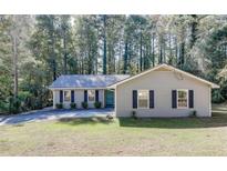 Charming single-story home with blue door, dark shutters, and a well-maintained front lawn surrounded by trees at 1373 W Prospect Dr, Lawrenceville, GA 30043
