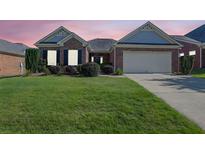 Charming brick home with a well-manicured lawn and two-car garage under a sky painted with hues of pink and orange at twilight at 1550 Rolling View Dr, Cumming, GA 30040
