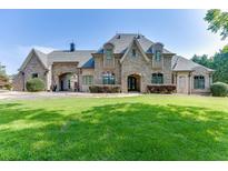 Stunning stone home with arched entryway and manicured lawn exudes curb appeal and timeless elegance at 2871 Hosch Valley Rd, Buford, GA 30519
