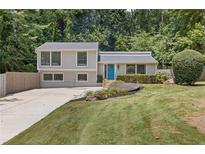 Charming home featuring a well-maintained yard, inviting blue door, and lush landscaping at 231 Cross Gate Dr, Marietta, GA 30068