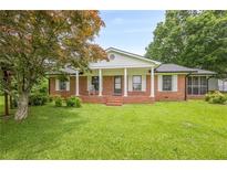 Charming brick home featuring a covered front porch and well-maintained lawn in a serene setting at 5709 Center Hill Church Rd, Loganville, GA 30052