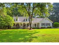 Charming one-story home featuring a welcoming front porch with rocking chairs and lush landscaping at 207 Lees Lake Rd, Fayetteville, GA 30214