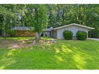 Charming ranch-style home with stone accent and mature trees, situated on a lush green lawn at 1328 Hidden Hills Pkwy, Stone Mountain, GA 30088