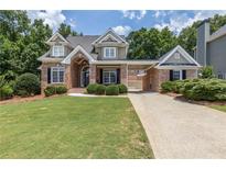 Charming brick home featuring a well-manicured lawn, arched entryway, and a convenient covered parking area at 501 Highwater Pass, Canton, GA 30114