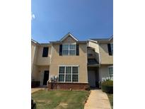 Charming townhome with tan facade, multiple windows, and a neatly maintained lawn at 2390 Coach Way, Jonesboro, GA 30236