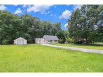 Charming single-story home with a large front yard and detached garage, surrounded by lush trees at 60 Newton Ridge Dr, Covington, GA 30014