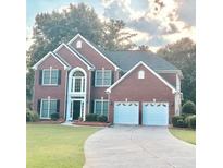 Charming brick home featuring a manicured lawn, black shutters, and a two-car garage at 10770 Glenhurst Pass, Duluth, GA 30097