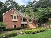 Charming brick home with bay window, manicured landscaping, and inviting staircase to a covered porch at 4027 Wood Acres Court Ct, Duluth, GA 30096