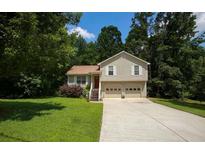 Charming two-story home featuring a two-car garage, red front door, and a well-maintained lawn surrounded by mature trees at 177 Rustin Dr, Dallas, GA 30157